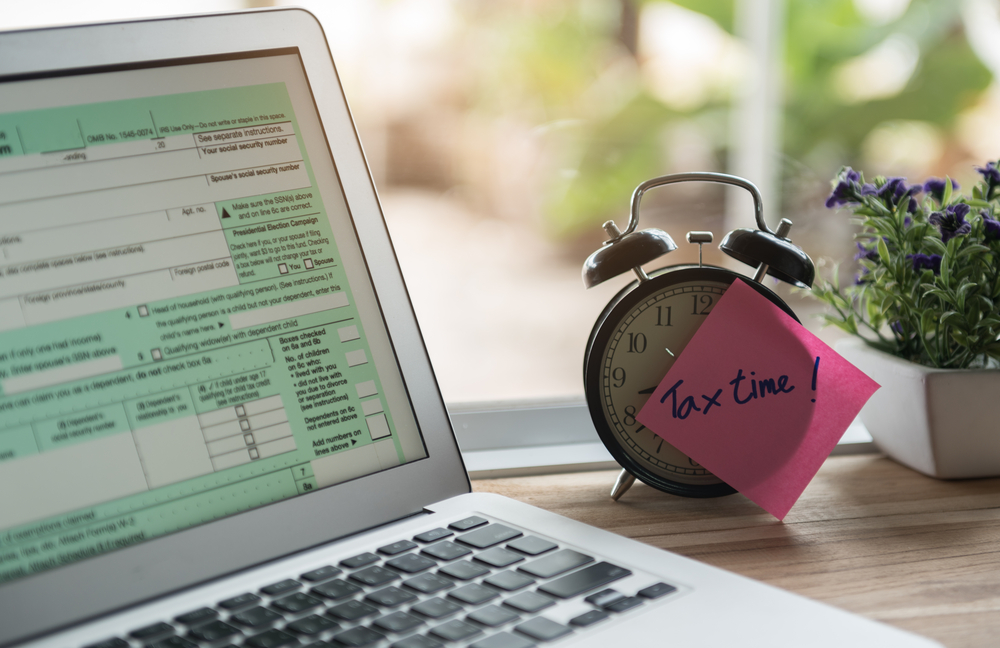 tax time post-it on alarm clock and Individual income tax form online.