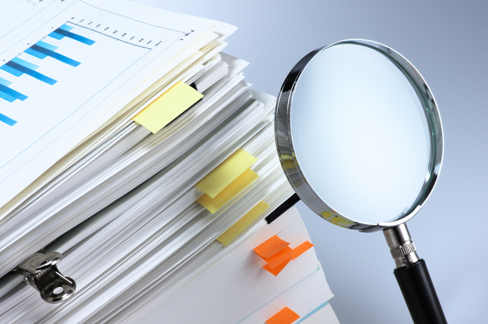 Scanning business documents. Magnifying glass and stack of documents.